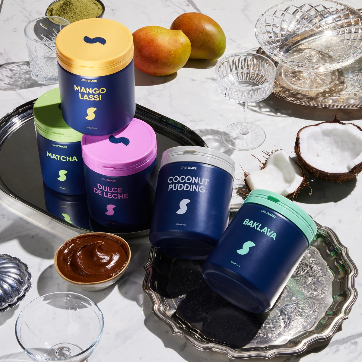 Five Daily Shake protein powder jars with mango, coconut and matcha ingredients