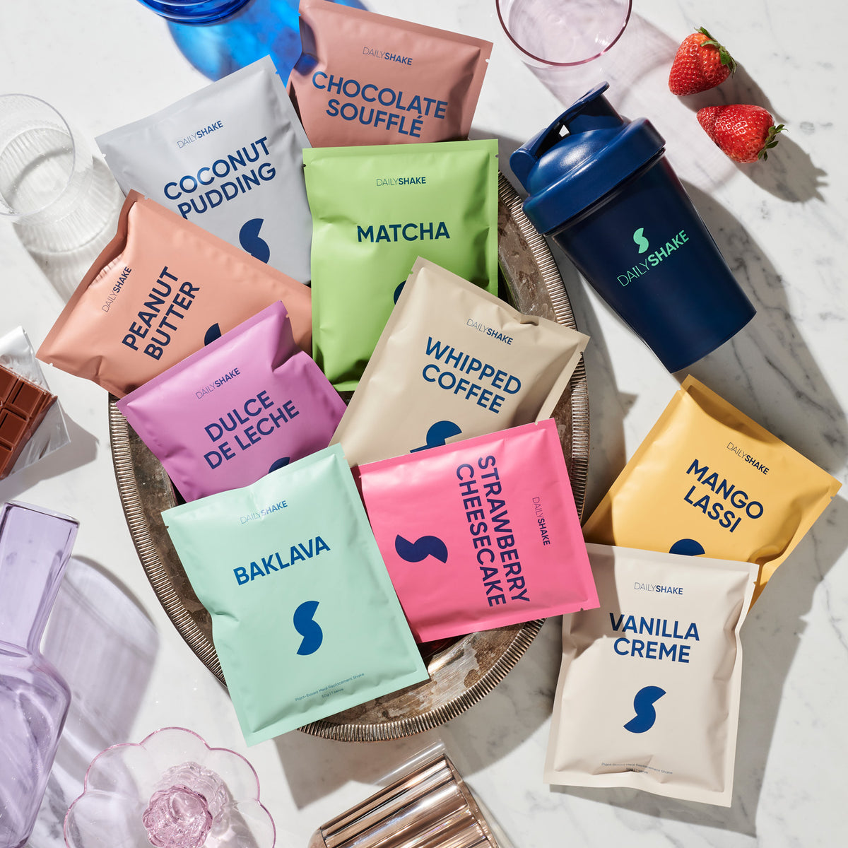 Colourful plant protein powder sachets with strawberries and a shaker